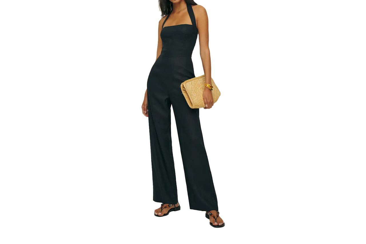 Individual in a sleeveless jumpsuit holding a woven clutch bag