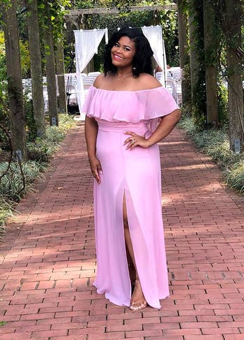 a reviewer in an off-shoulder ruffled pink gown with a leg slit, posing outdoors