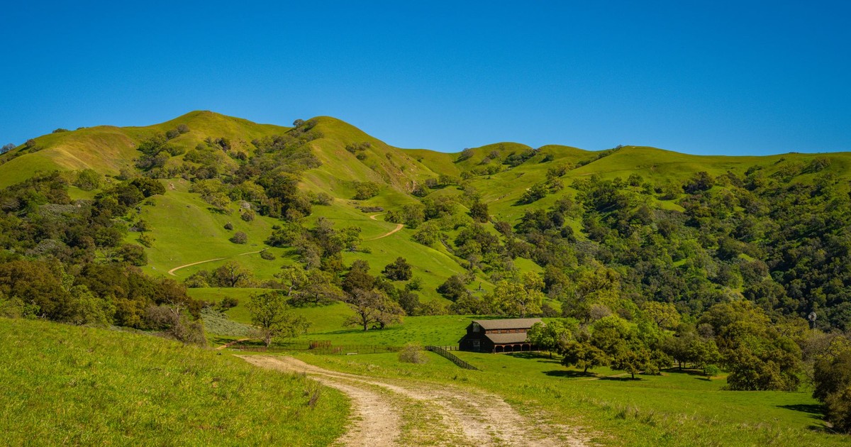 Serene view of lush green hills and rustic barn in Sunol, California.