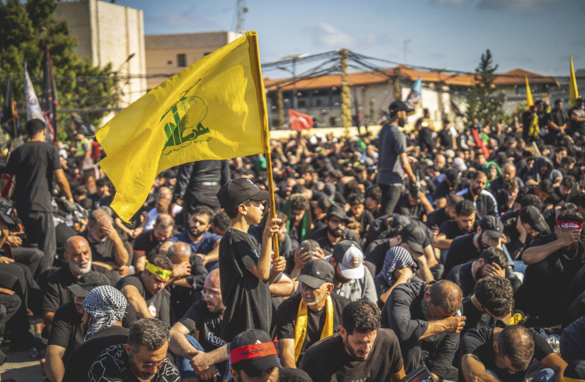 A boy holds a yellow Hezbollah flag while walking among a crowd during a mourning ceremony in the southern suburbs of Beirut, Lebanon, on June 26, 2026. (credit: Nael Chahine / Middle East Images / AFP via Getty Images)