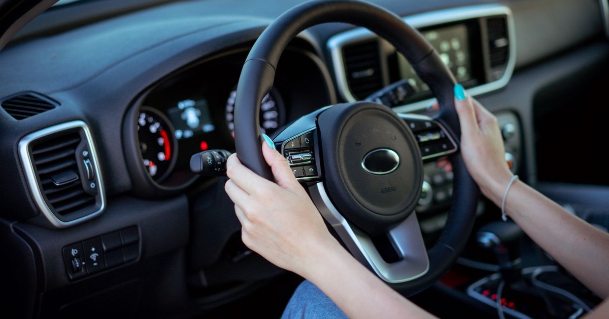 Close-up of a woman's hands on a steering wheel in a modern car interior.