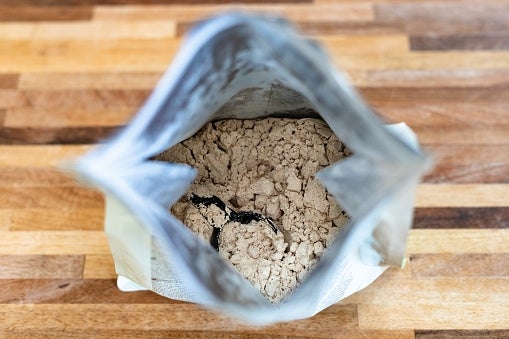 Open bag of protein powder on a wooden surface