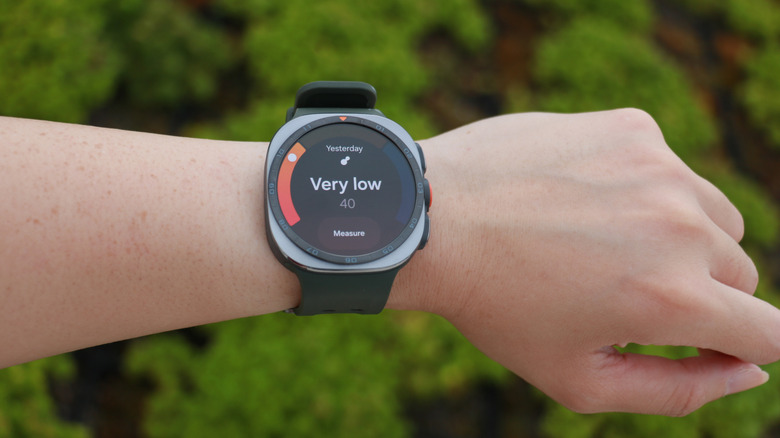 The Galaxy Watch Ultra 2 on a person's wrist raised up in front of a field, its screen showing antioxidant test results saying
