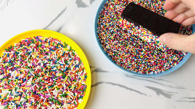 Dipping ice cream sandwiches into sprinkles