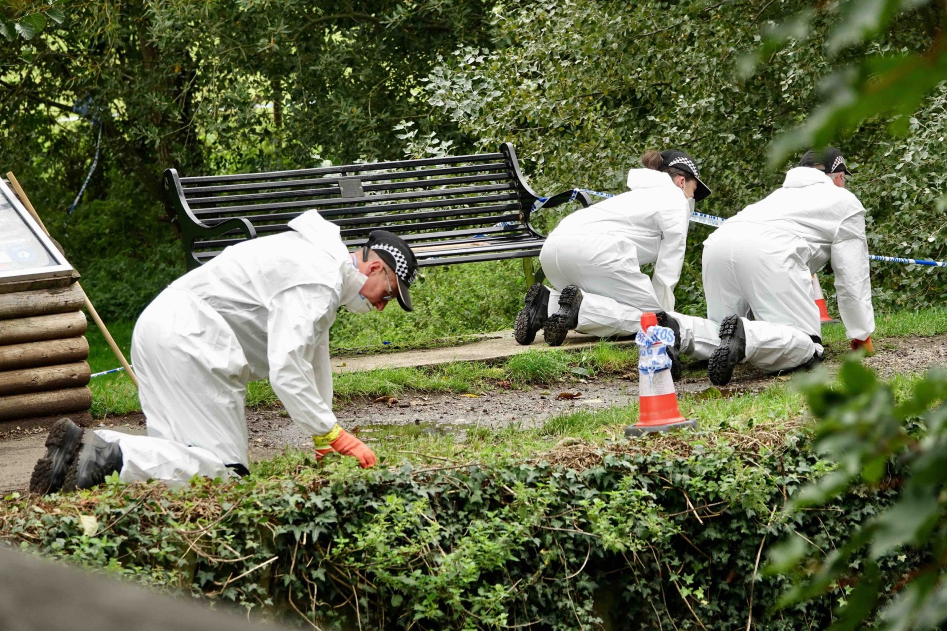 Police in white suits searching the ground.