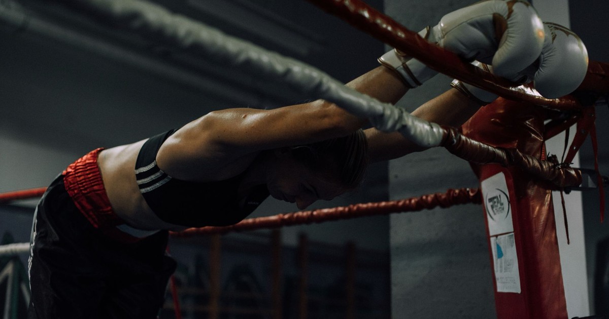 A dedicated female boxer rests in the ring, showcasing strength and perseverance.