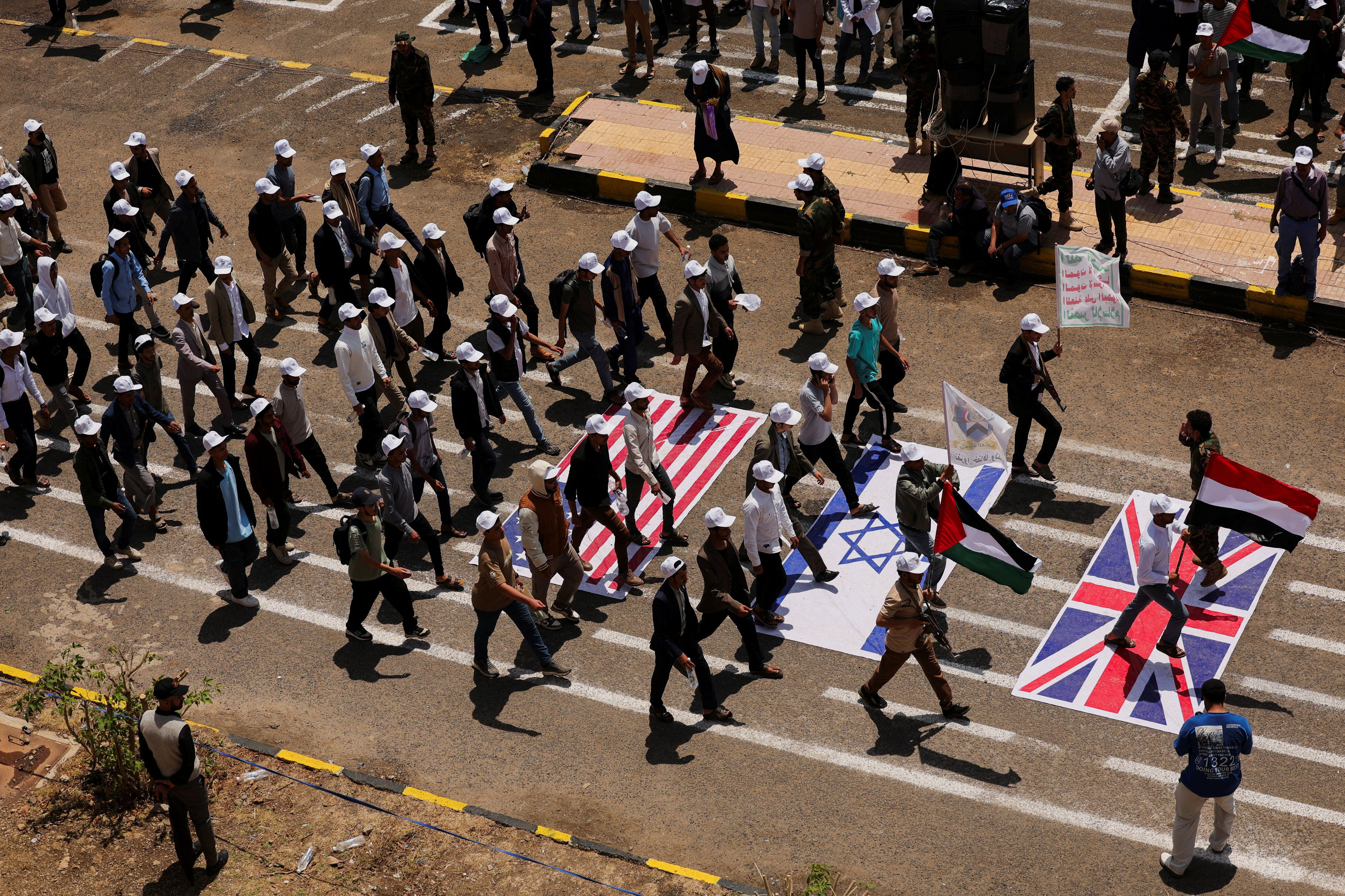 Students walk on U.S., Israeli and U.K. flags as they parade at Sanaa University campus to show support for the Houthis amid an escalation with Saudi Arabi (Reuters)