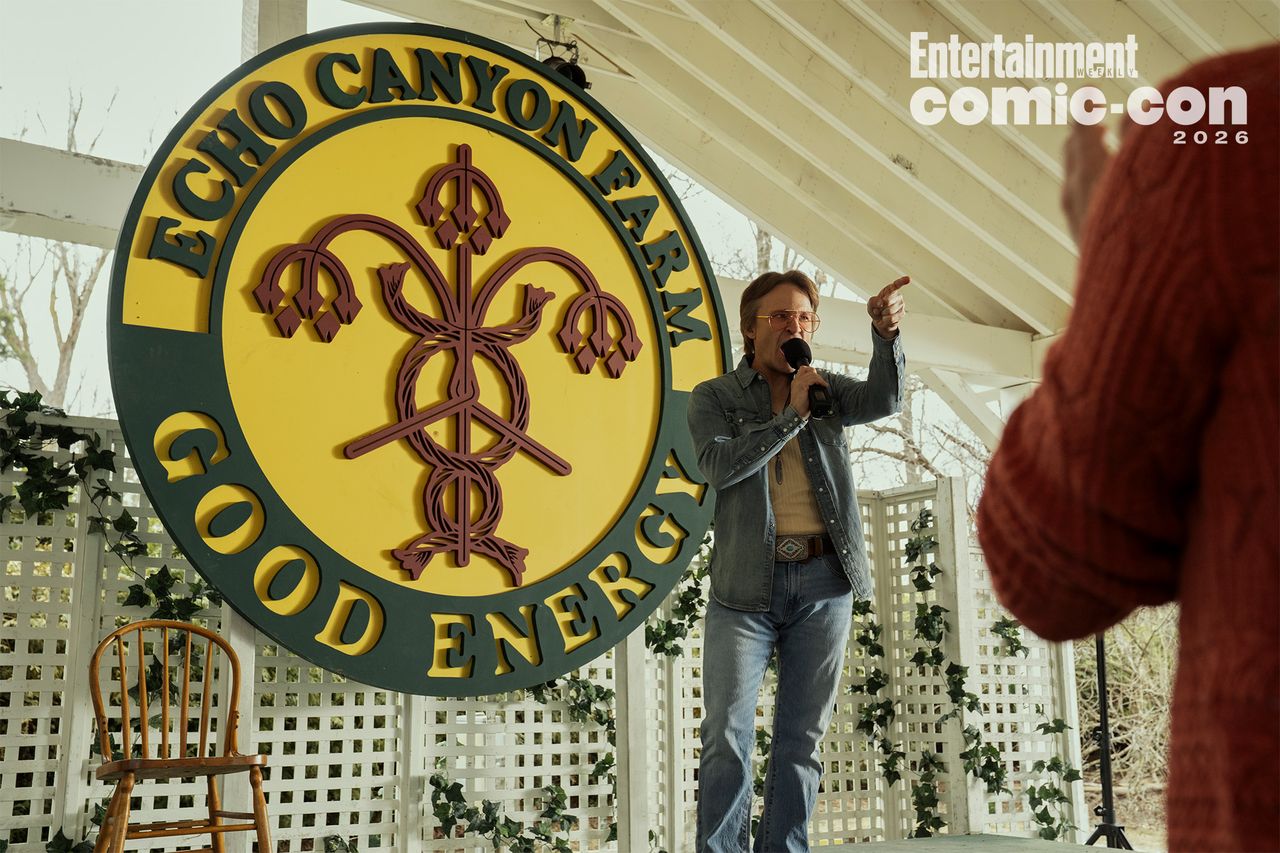 A man speaking on a microphone near a large Echo Canyon Farm sign