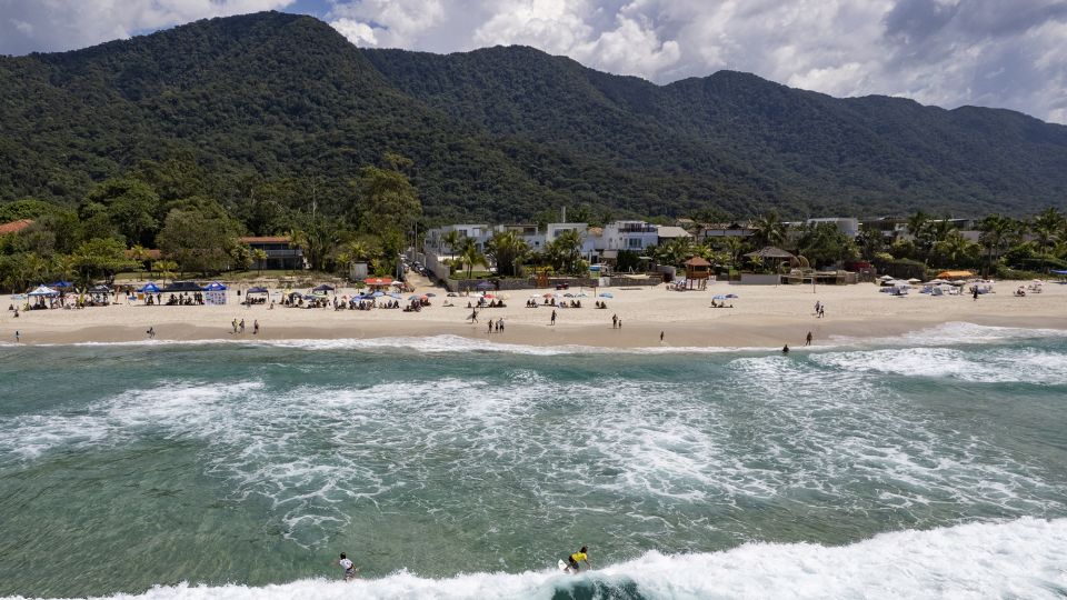 Surfers ride the waves during a local tournament at Maresias beach in São Sebastião in November 2021. - Andre Penner/AP