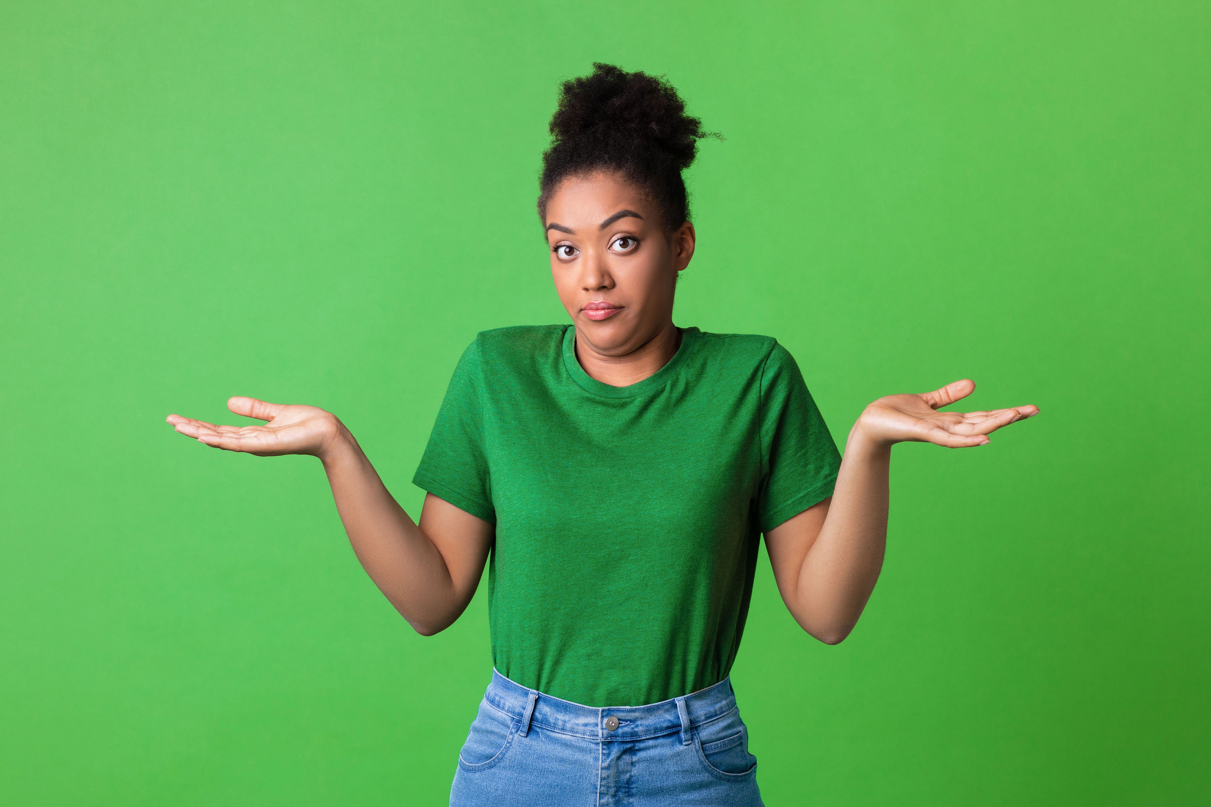 Person with an uncertain expression, shrugging with palms up. Wearing a casual t-shirt and jeans