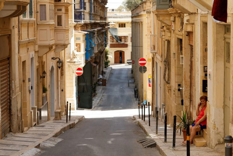 A woman sits in the shade on the doorstep of her home during a power outage amid a heatwave in Valletta, Malta, July 22, 2026. REUTERS/Darrin Zammit Lupi