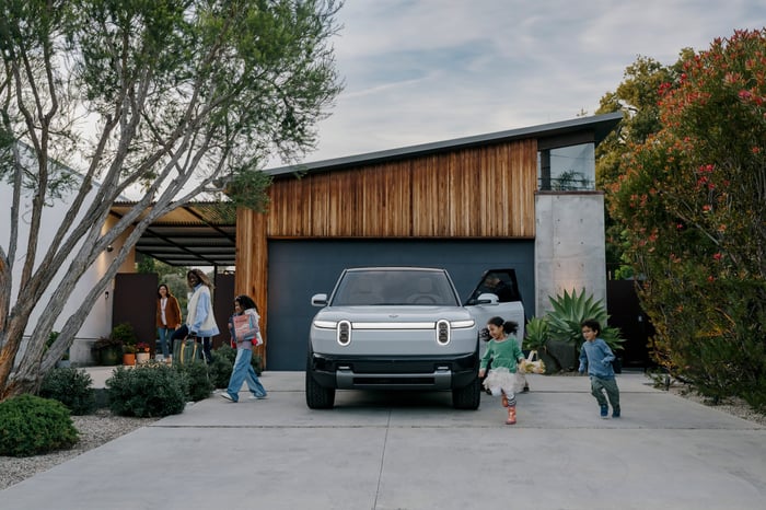Rivian's R2 parked in front of a family home.