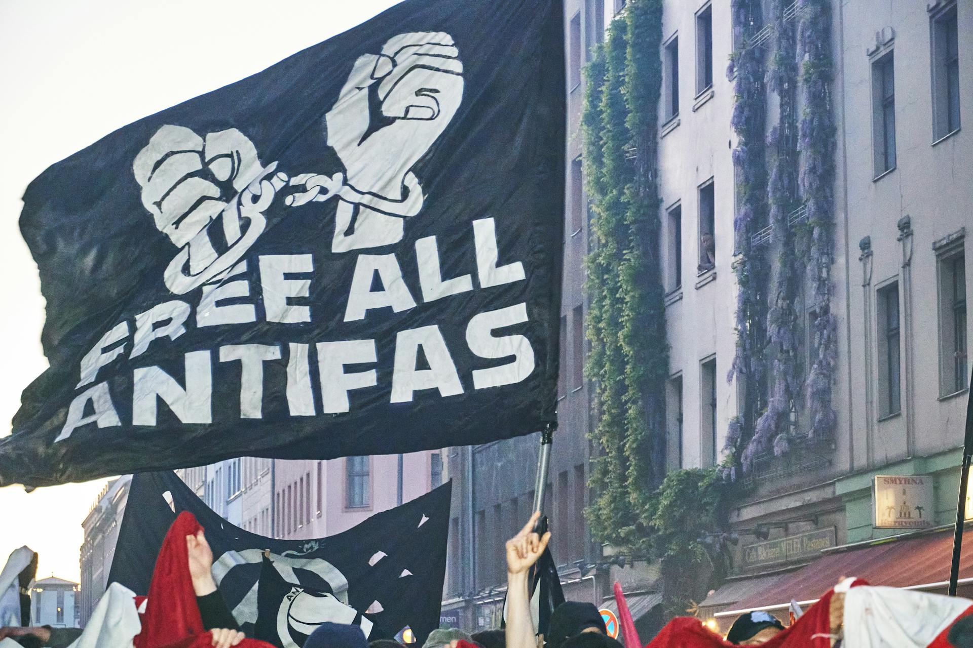 Protesters hold a black banner while walking on a city street.