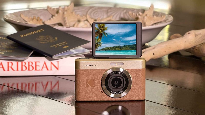 The Kodak PixPro C1 camera on a coffee table, showing a picture of an island, with two passports in the background
