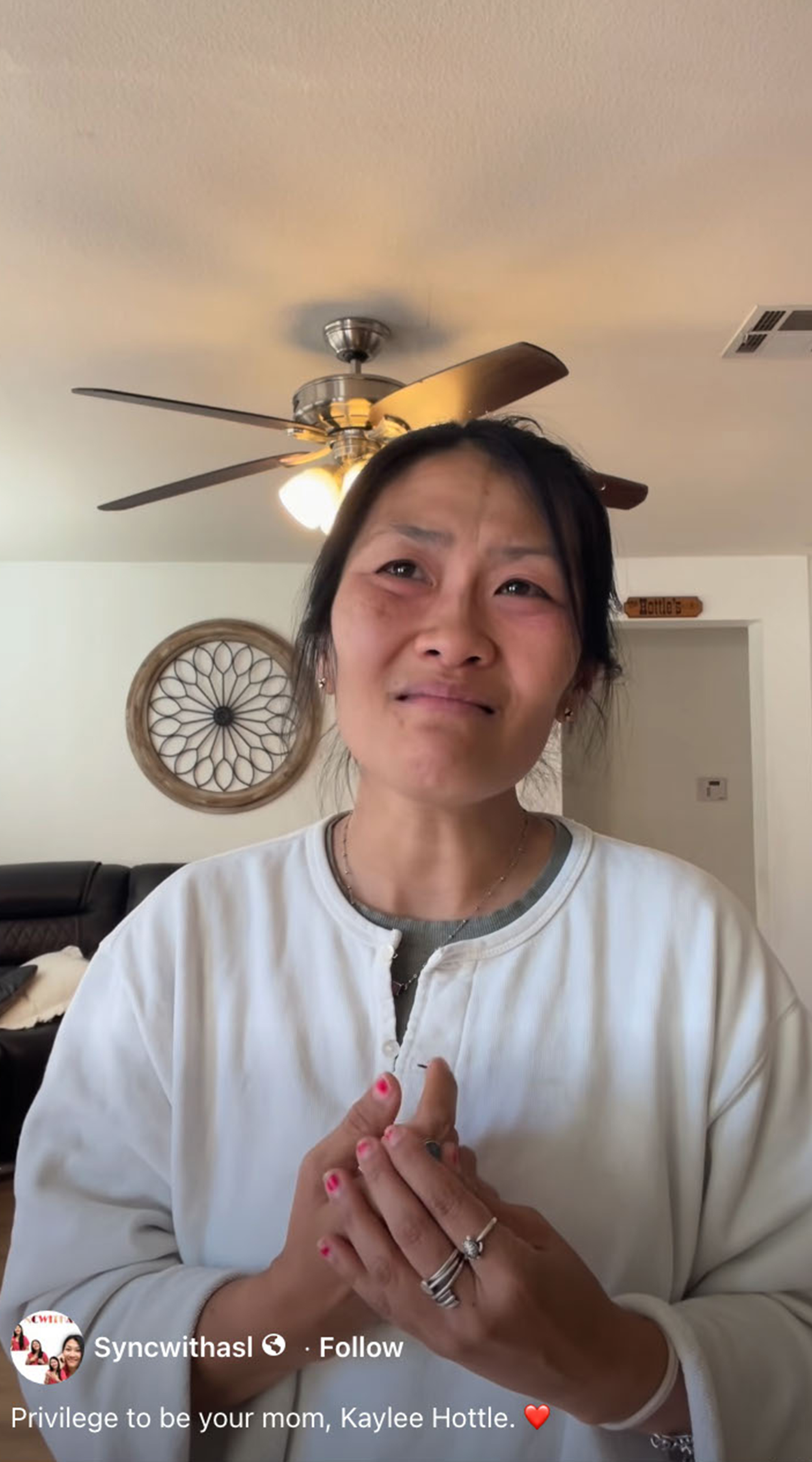 A tearful Asian woman looking up, with her hands clasped.