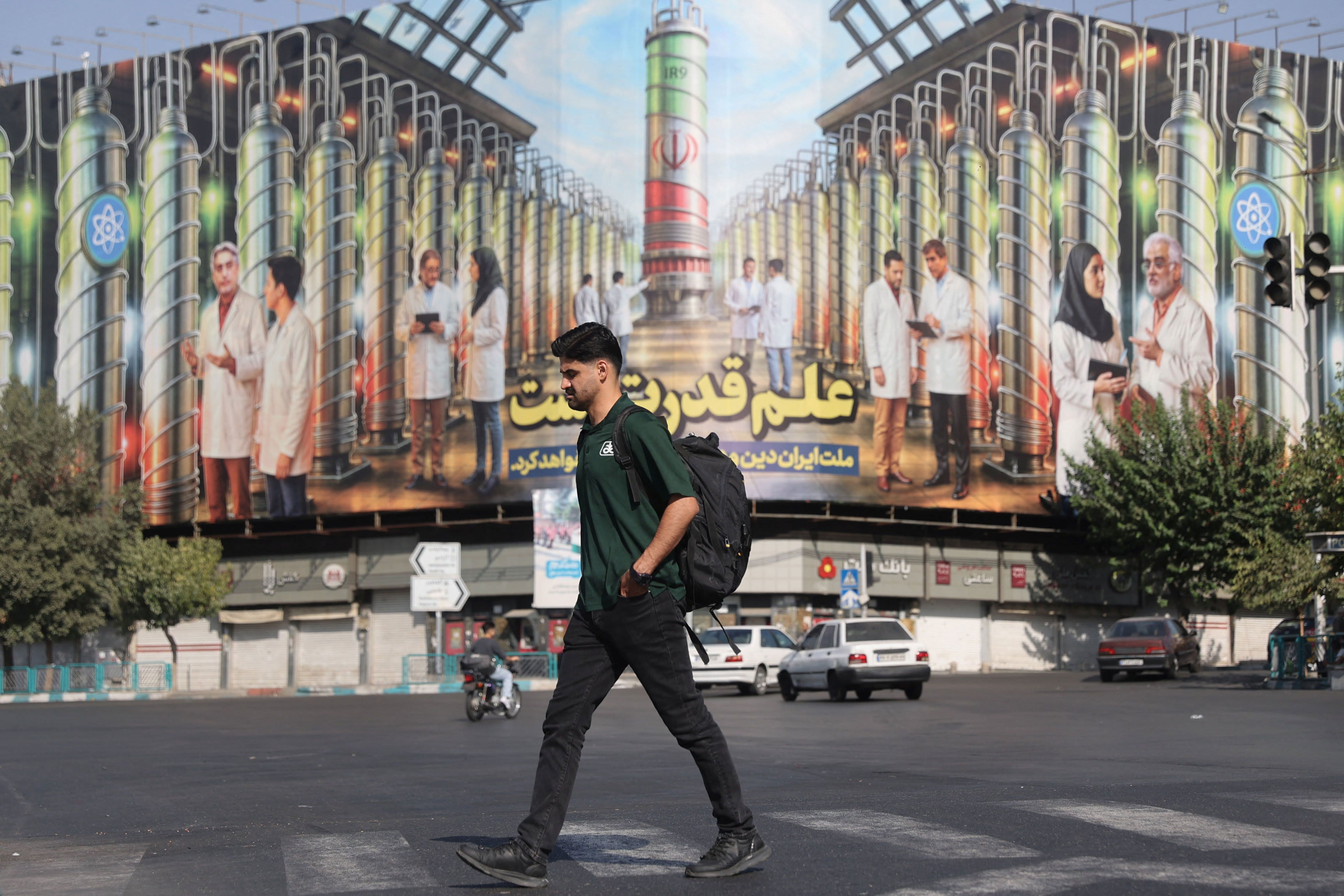 A man crosses the street, past a billboard showing Iranian centrifuges and nuclear scientists killed in Israeli strikes, in Tehran, Iran, August 29, 2025