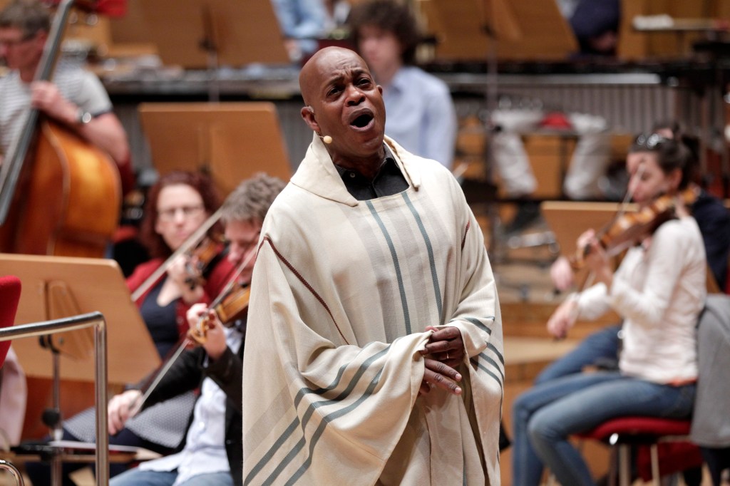 Jubilant Sykes performing in a light-colored tunic with an orchestra.