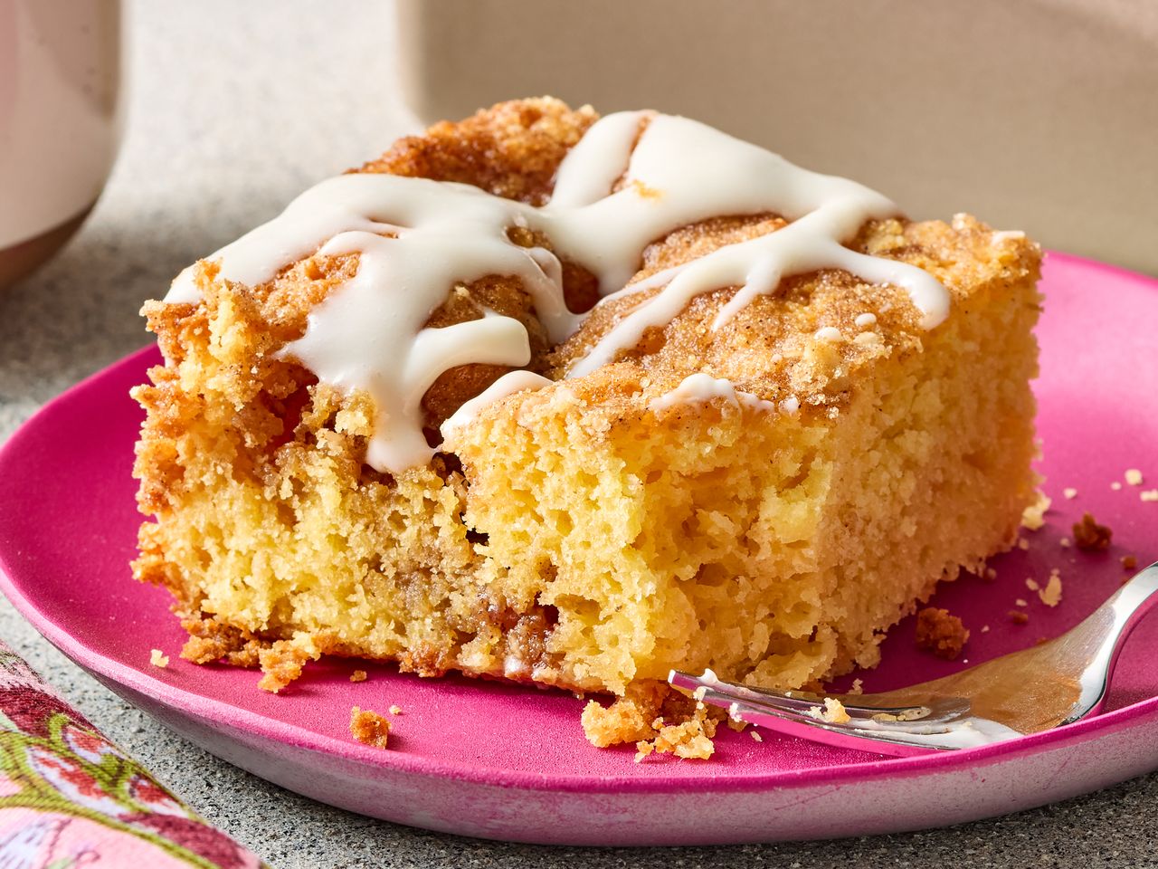 Slice of cake with icing drizzle on a pink plate with a fork