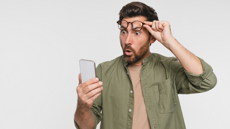 Man looking at phone with surprised expression