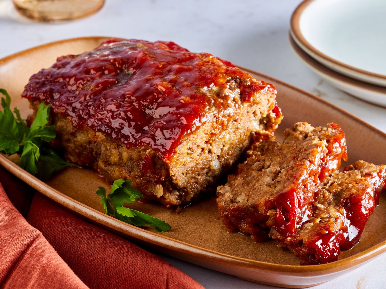 A platter with sliced brown sugar meatloaf with ketchup glaze