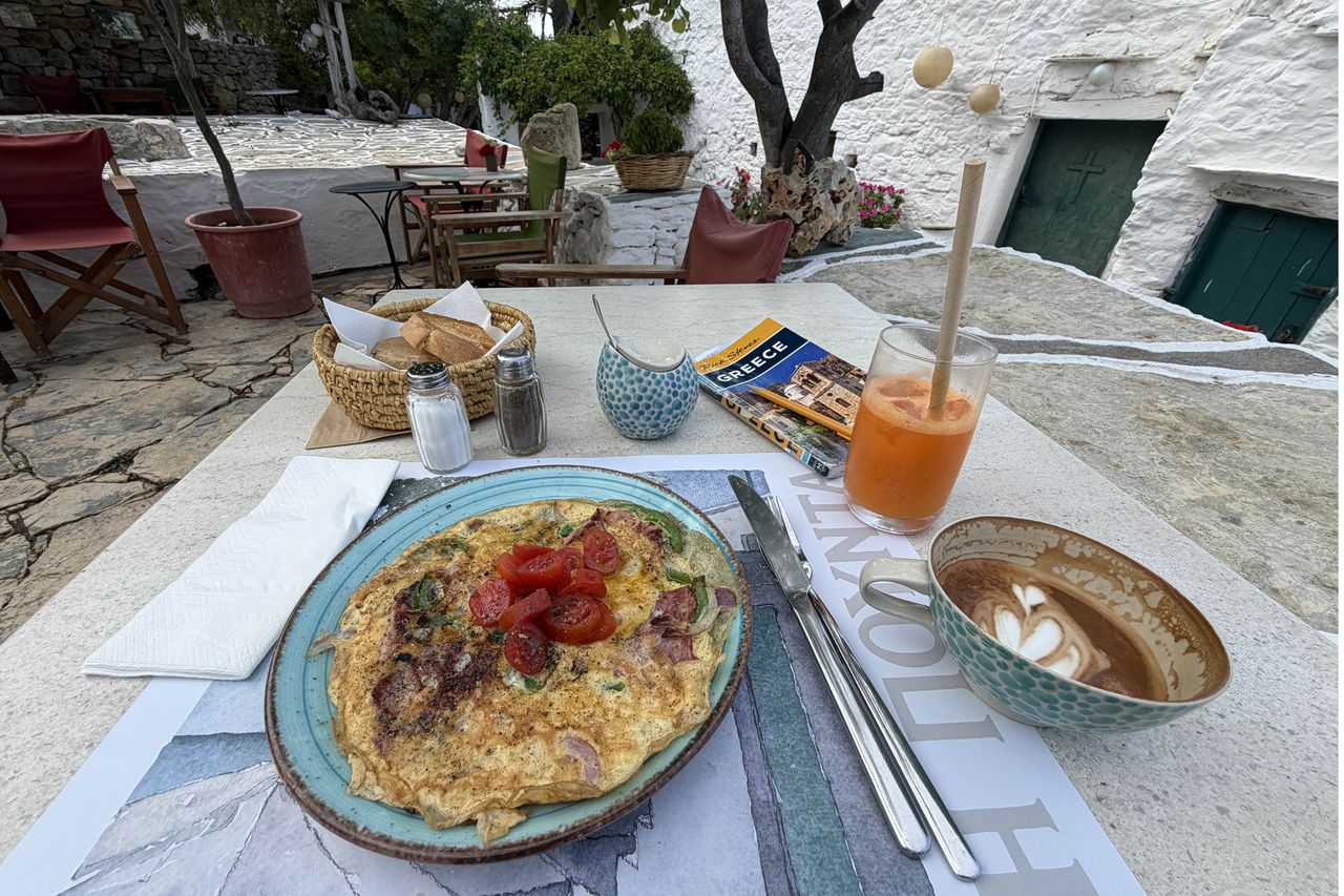 A table set with a plate of food a drink and a cappuccino outdoors