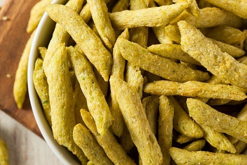 A bowl filled with crunchy, textured green vegetable sticks set on a wooden surface