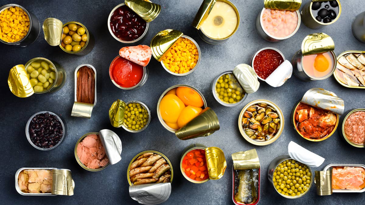 food-background-in-tin-cans-canned-vegetables-beans-fish-and-fruits-on-a-stone-background-food-banner-top-view