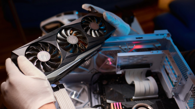 Close-up of hands handling a GPU above an open PC