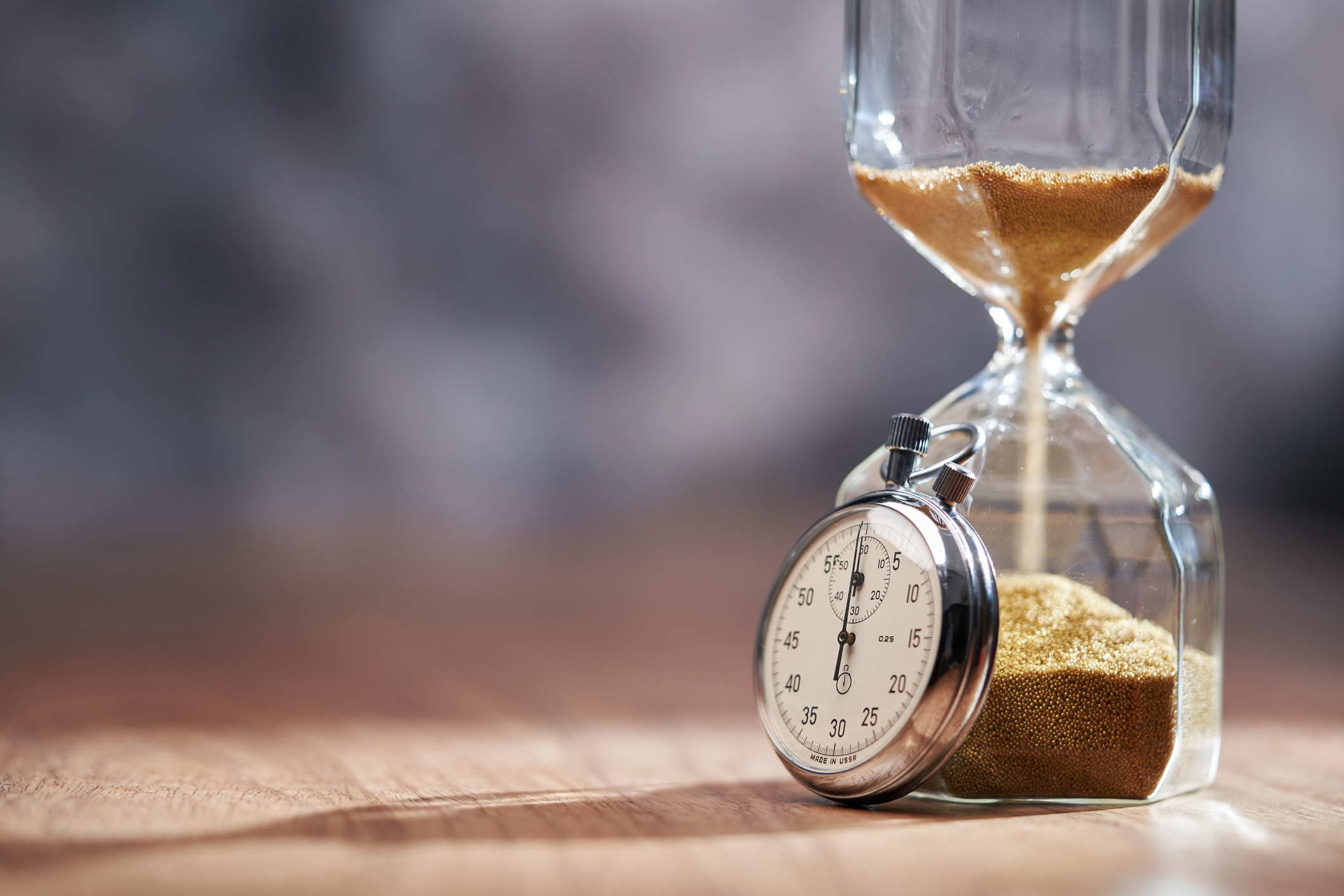 antique hourglass and stopwatch on wooden table