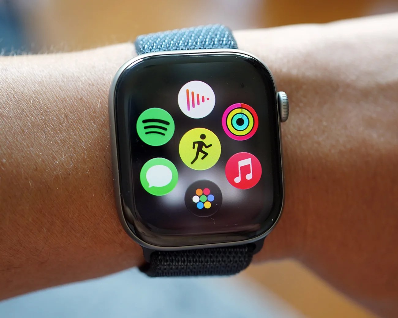 Smartwatch with a black case and blue fabric strap displaying colorful app icons on the screen.