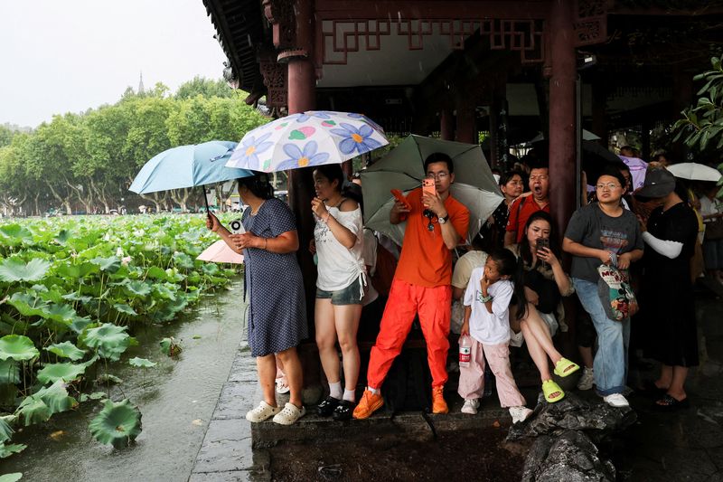 People shelter from the rain under a roof in Hangzhou