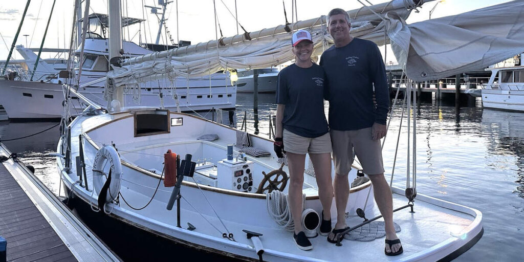 Two crew members stand on a white sailboat at a marina before a Treasure Coast Sailing Adventures sunset sail in Stuart, Florida.