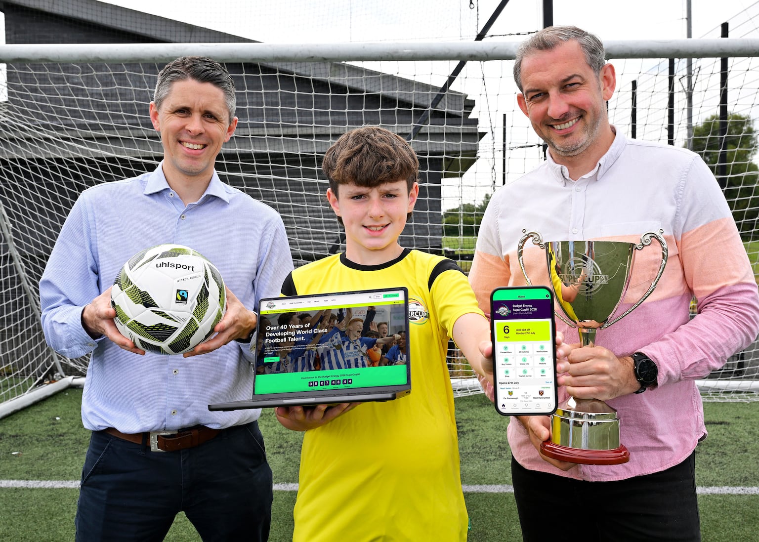 Sam Gamble, Tournament Co-ordinator of the Budget Energy SuperCupNI, Ryan Young, Creative Partner at Astutely, and budding young footballer Theo Lever are pictured launching the new official Budget Energy SuperCupNI website and mobile app ahead of the 2026 tournament.