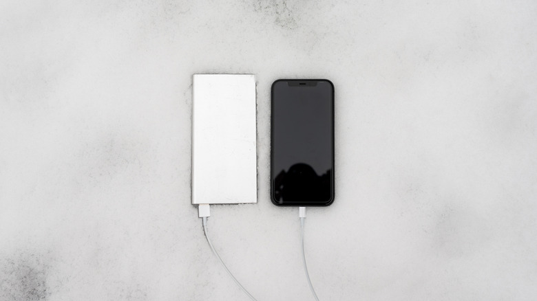 A power bank charging a phone in snow