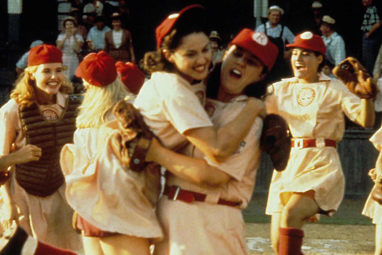 Women baseball players celebrating on the field appearing excited and joyful in a group embrace