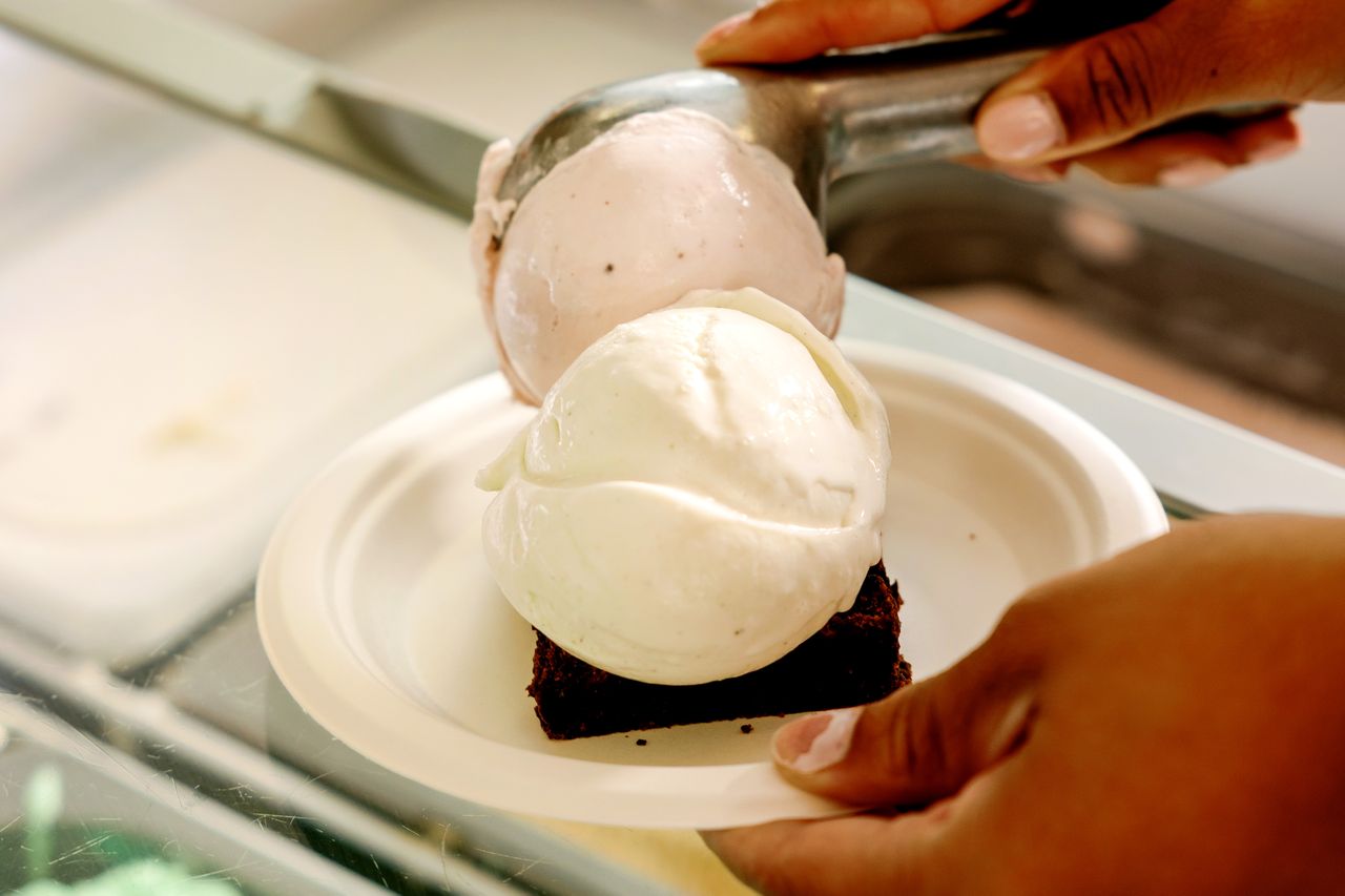 Two scoops of ice cream being served on a brownie in a bowl