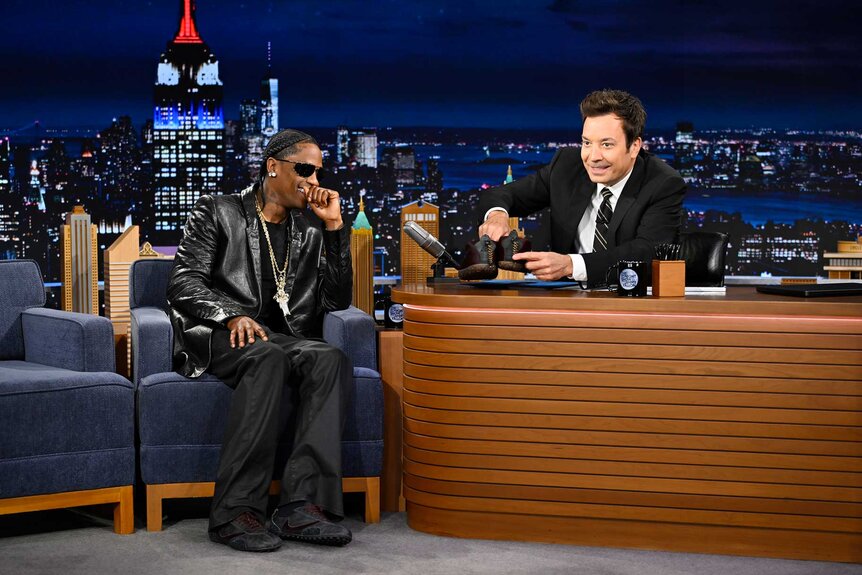 Travis Scott sitting next to Jimmy Fallon during The Tonight Show Starring Jimmy Fallon Season 13 Episode 130.