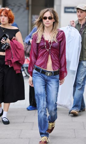Suki Waterhouse walking outdoors with others in the background