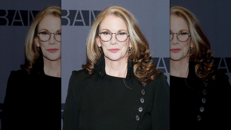 Melissa Gilbert smiles wearing round glasses and a black blazer
