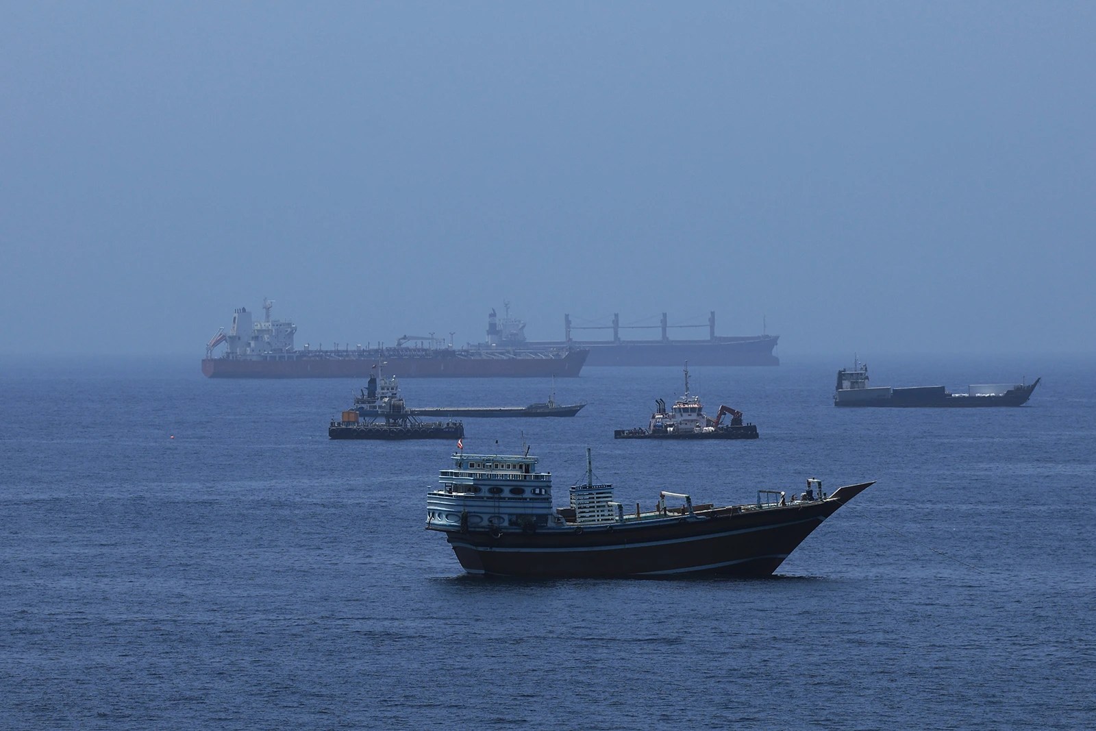 Commercial cargo vessels and crude oil tankers anchored in the Gulf of Oman near the Strait of Hormuz on June 21, 2026, off the coast of Muscat, Oman.