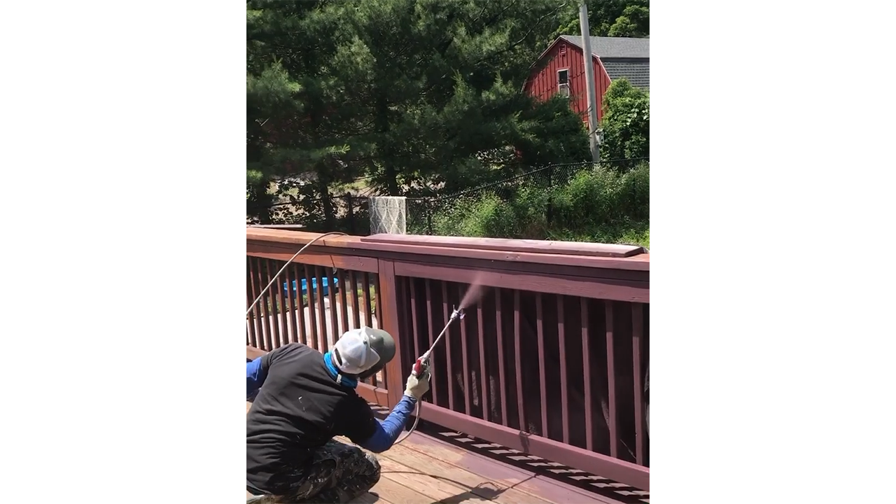 Applying walnut wood stain to deck balusters creating rich outdoor finish