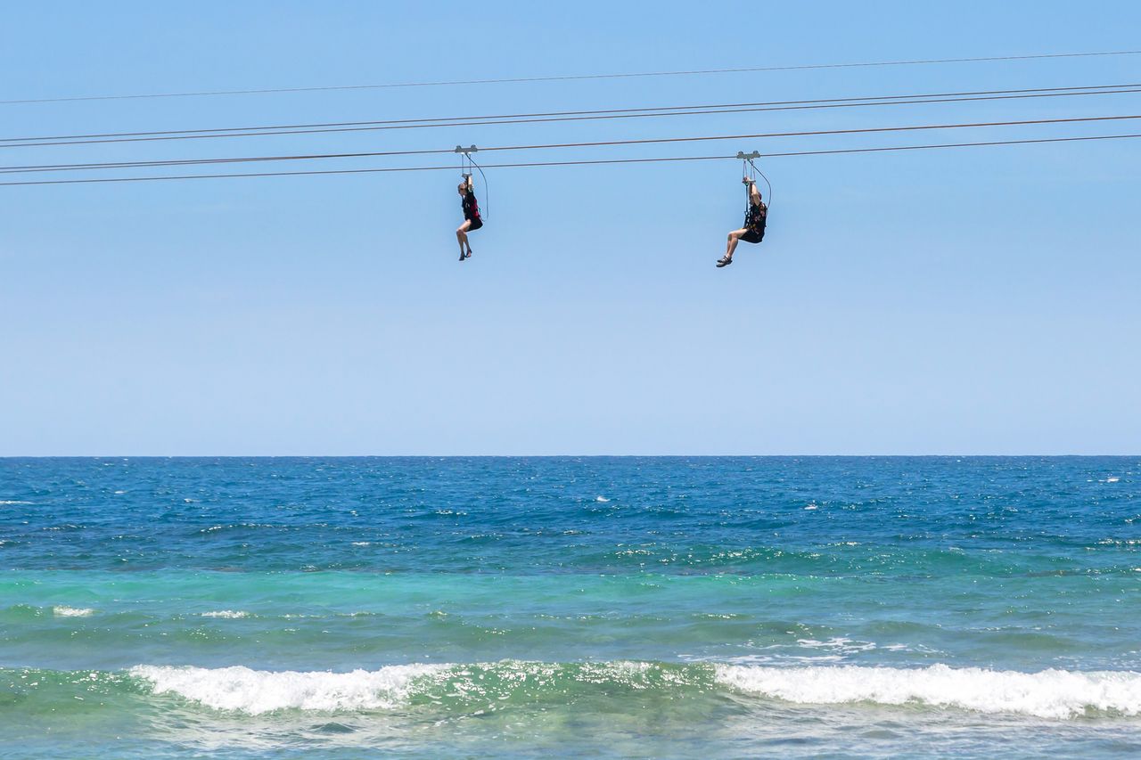 Cruise ship passengers riding the Dragon's Flight Zipline attraction on Royal Caribbean's private coastal peninsula of Labadee, Haiti