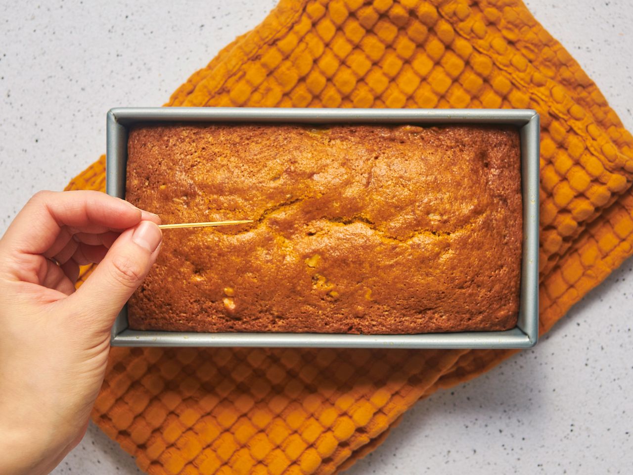 Testing banana bread doneness with toothpick.