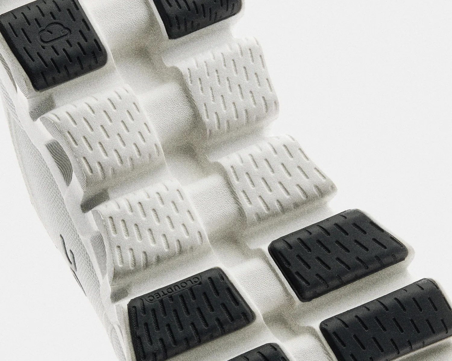 Close-up of a white shoe sole with black rubber traction pads and textured grooves.