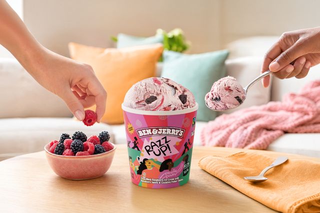 Scooping Ben Jerrys frozen dessert with a bowl of berries nearby