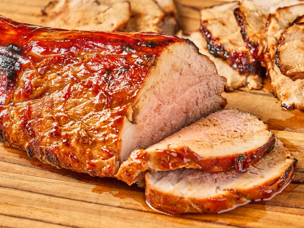 Sliced roasted pork tenderloin on a wooden cutting board