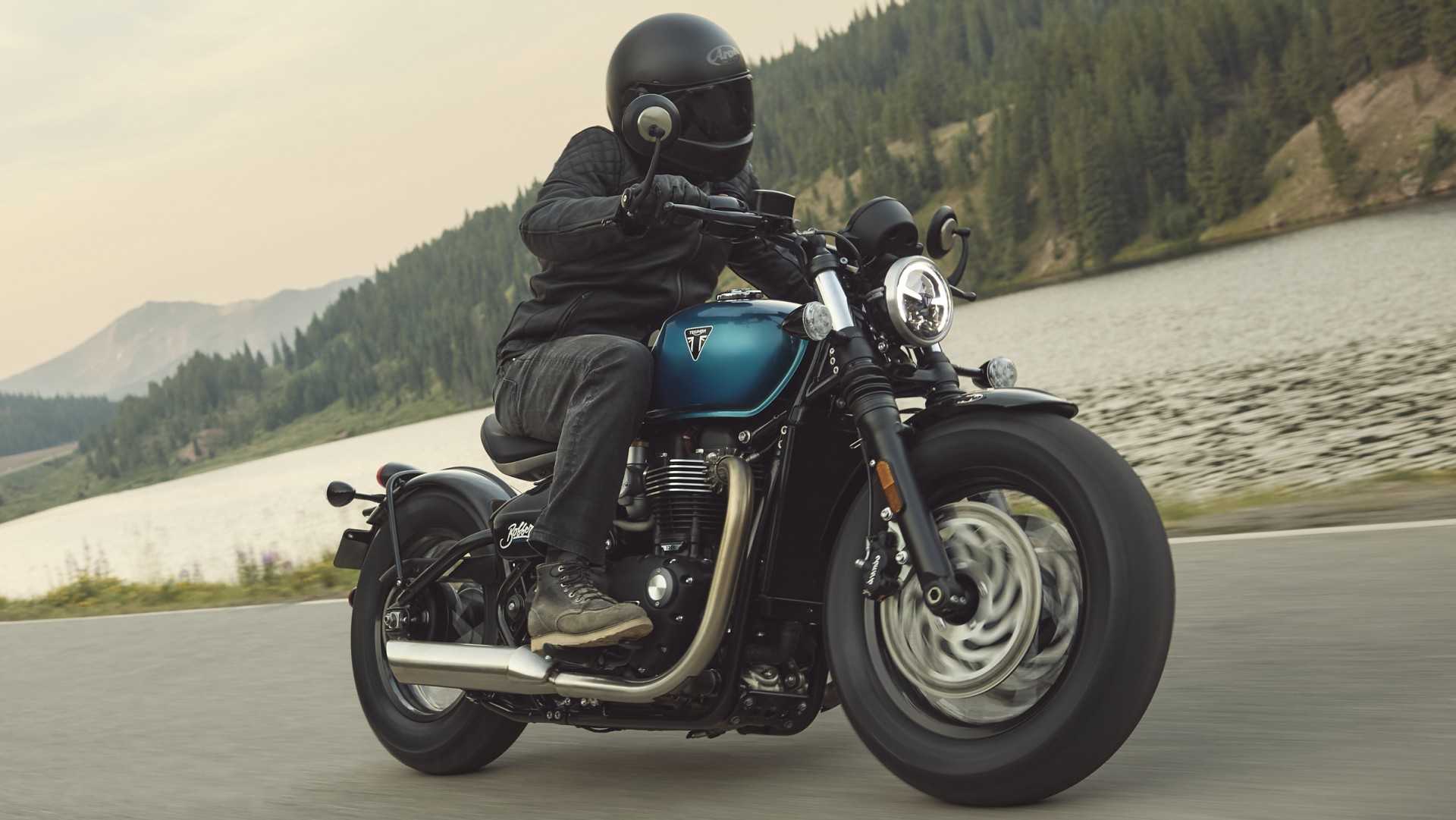 2026 Triumph Bonneville Bobber accelerating cozily along a mountain road, front third quarter accelerating view