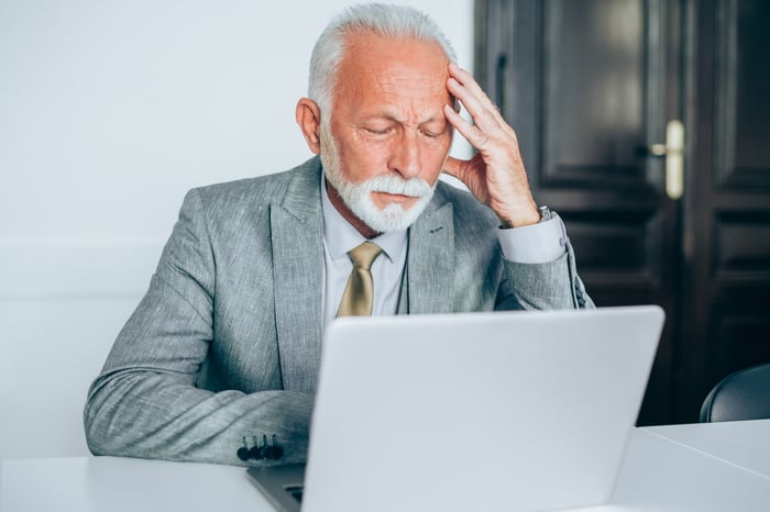 A person at a laptop has a serious expression.