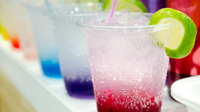 A row of different flavored Italian sodas in plastic cups