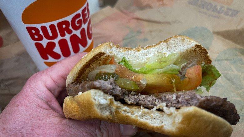 Someone holding a half-eaten Whopper at Burger King